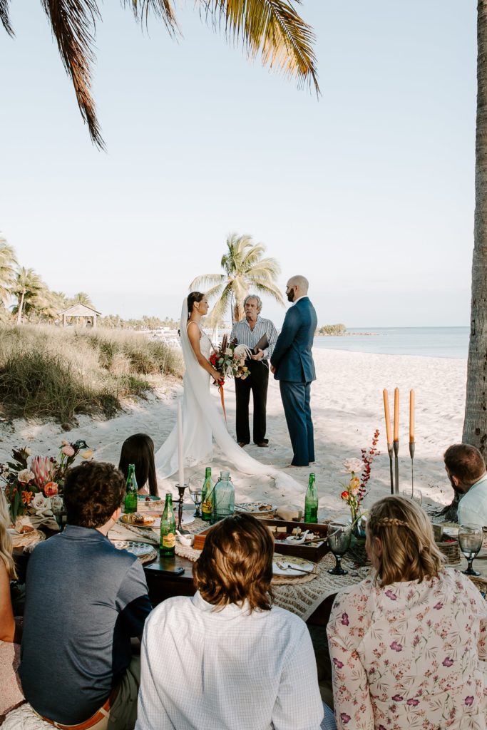 Couple standing between palm trees on Smathers beach during their intimate wedding ceremony