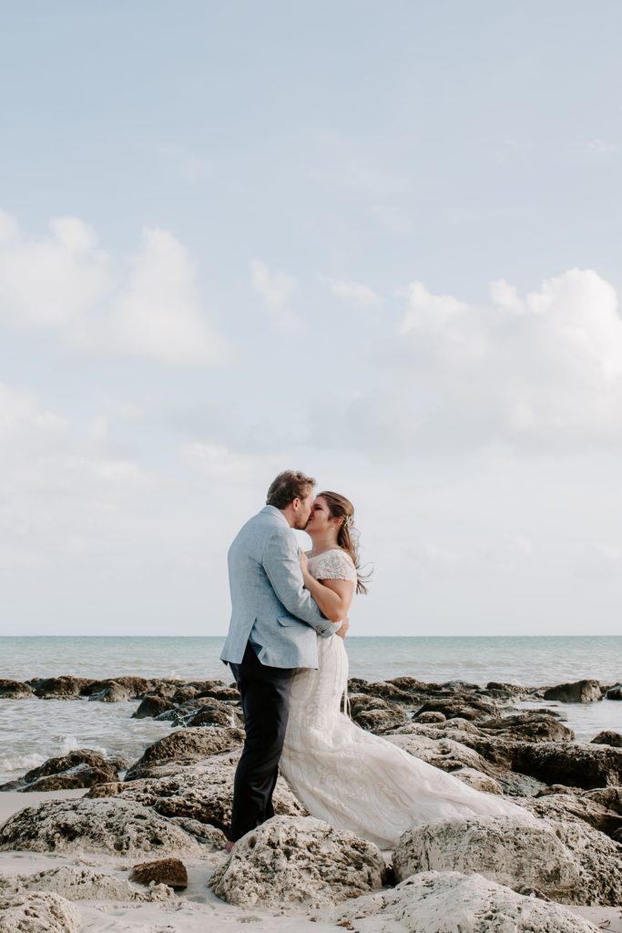 couple standing on rocks that lead out to the ocean as they share a kiss during their all day key west elopement