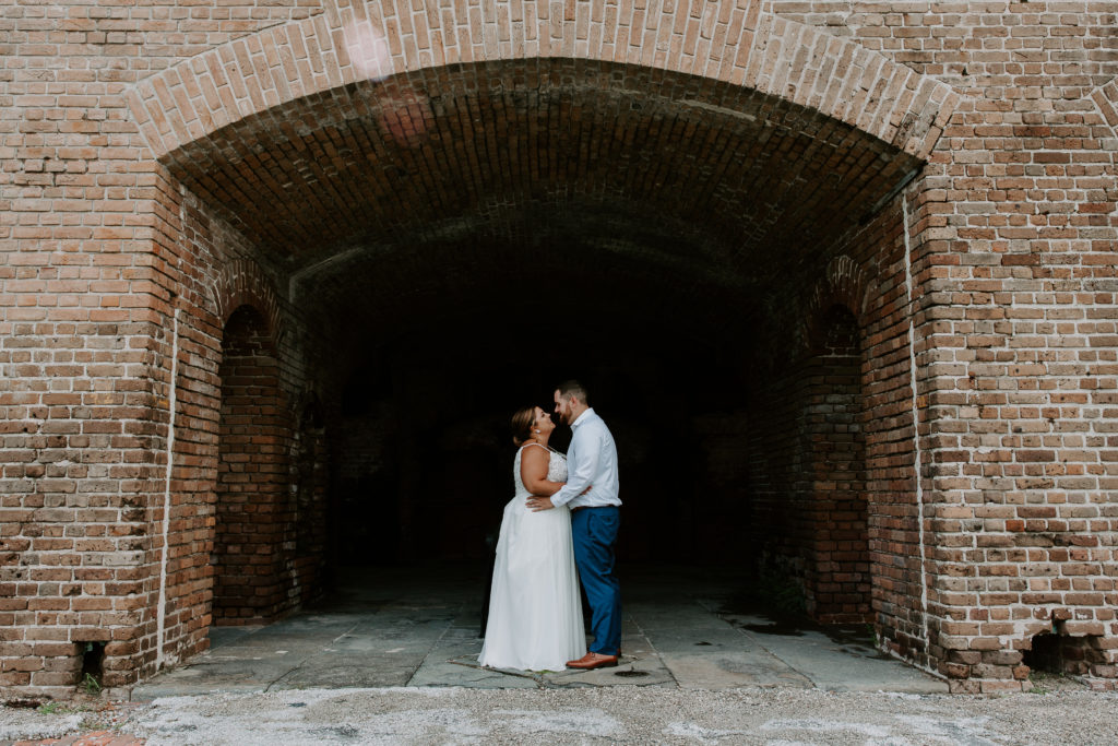 Couple standing nose to nose in an archway at Fort Zachery in Key West during their all day elopement