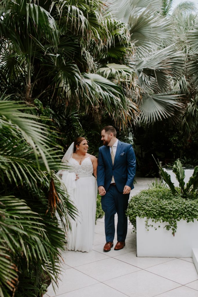 Couple holding hands and walking down a path at their Key West hotel during their all day adventure elopement