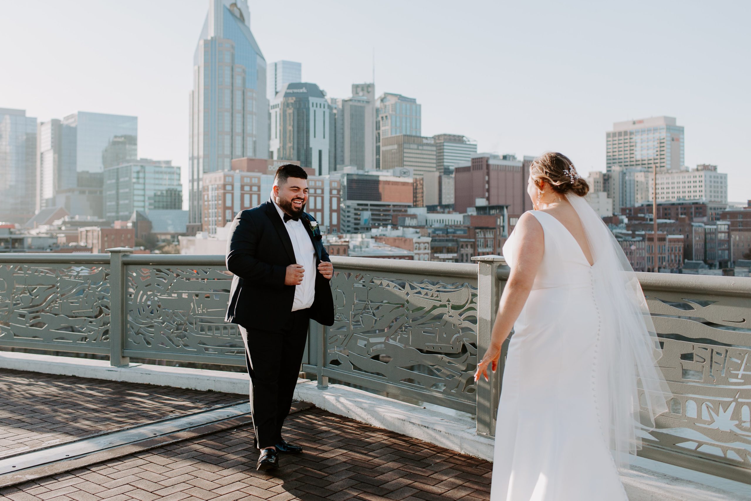 Man smiling so big after seeing his bride for the first time all dressed up as they do their first look on the pedestrian bridge in Nashville, Tennessee