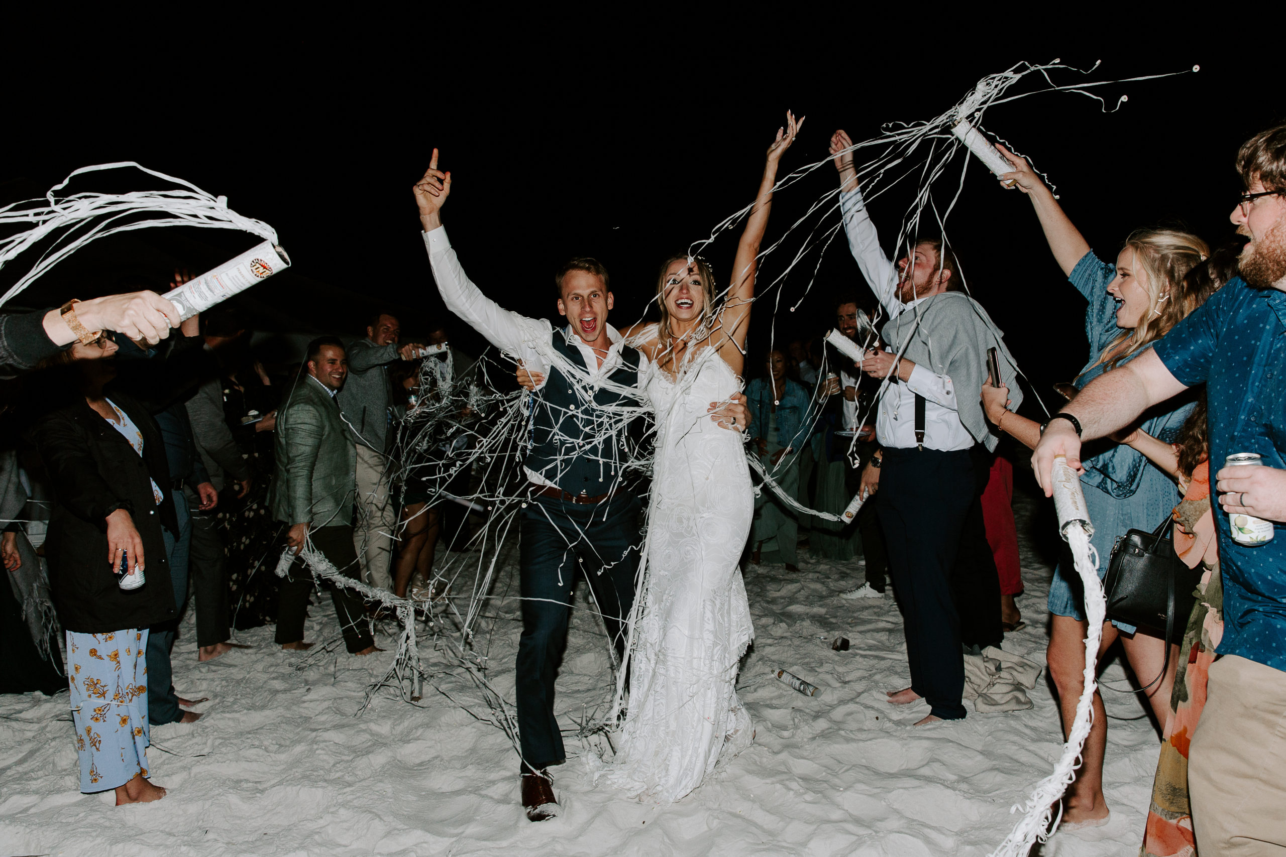 Couple running through their wedding guests at their ribbon send off on Miramar Beach in Destin, Florida