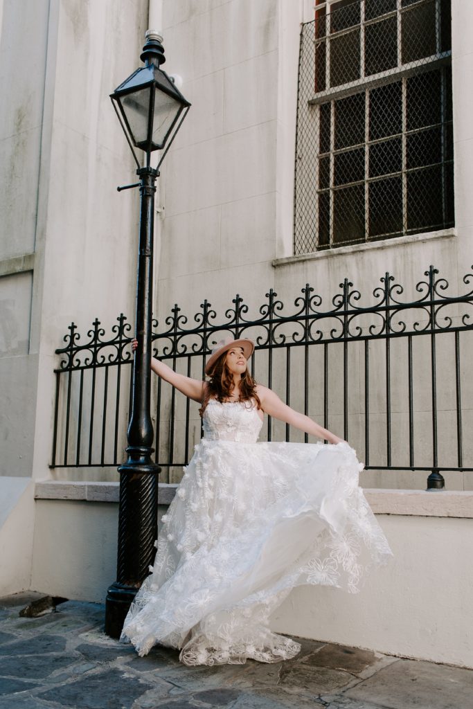 Woman hanging on to a light pole next to the Cathedral in Jackson Square during her New Orleans Elopement 