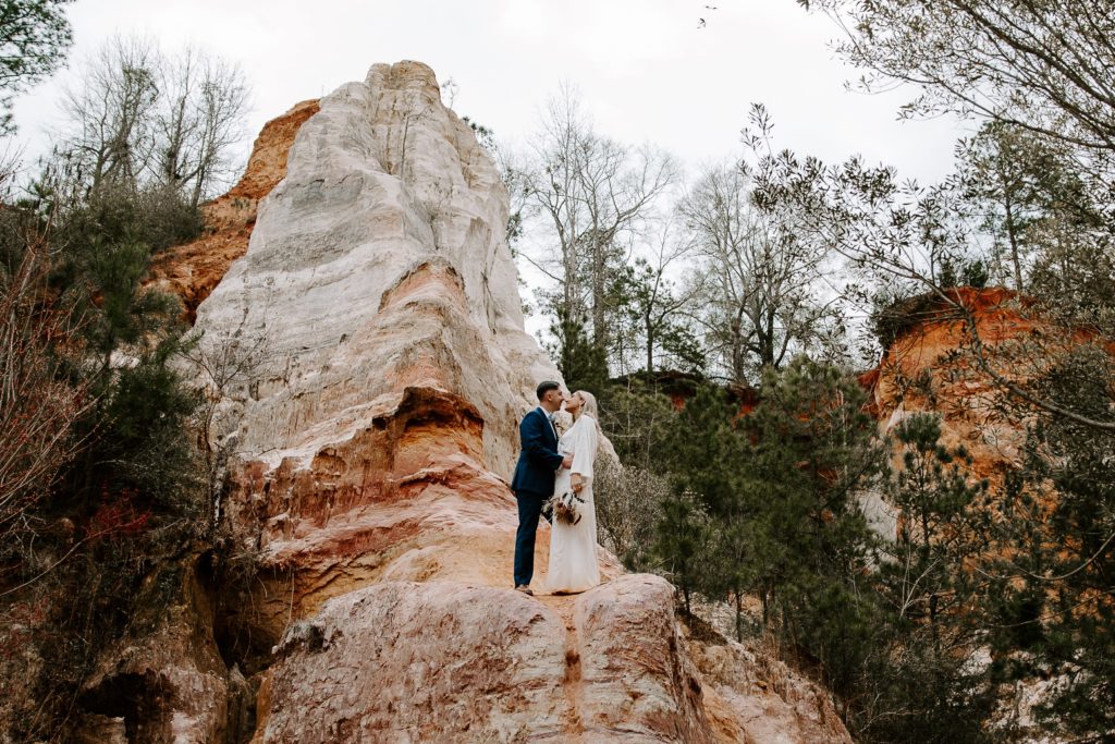 couple sharing a kiss on a ridge in wedding attire during their all day Georgia elopement