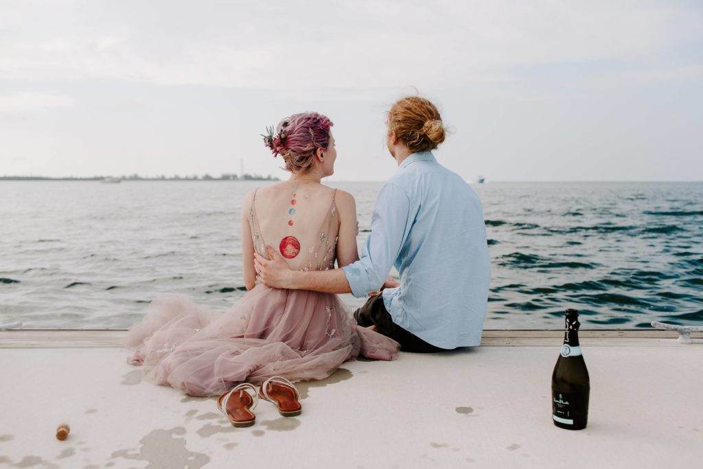 Couple sharing a bottle of champagne looking off over the water at the end of their all day Key West elopement