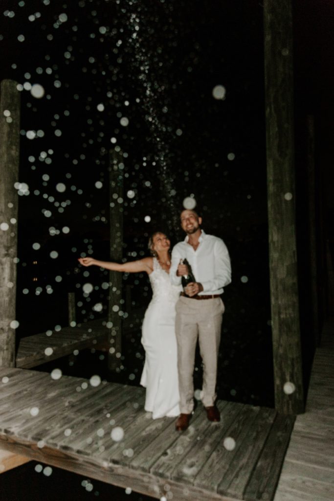 Couple popping a bottle of champagne at night after their all day Florida elopement in the Florida panhandle