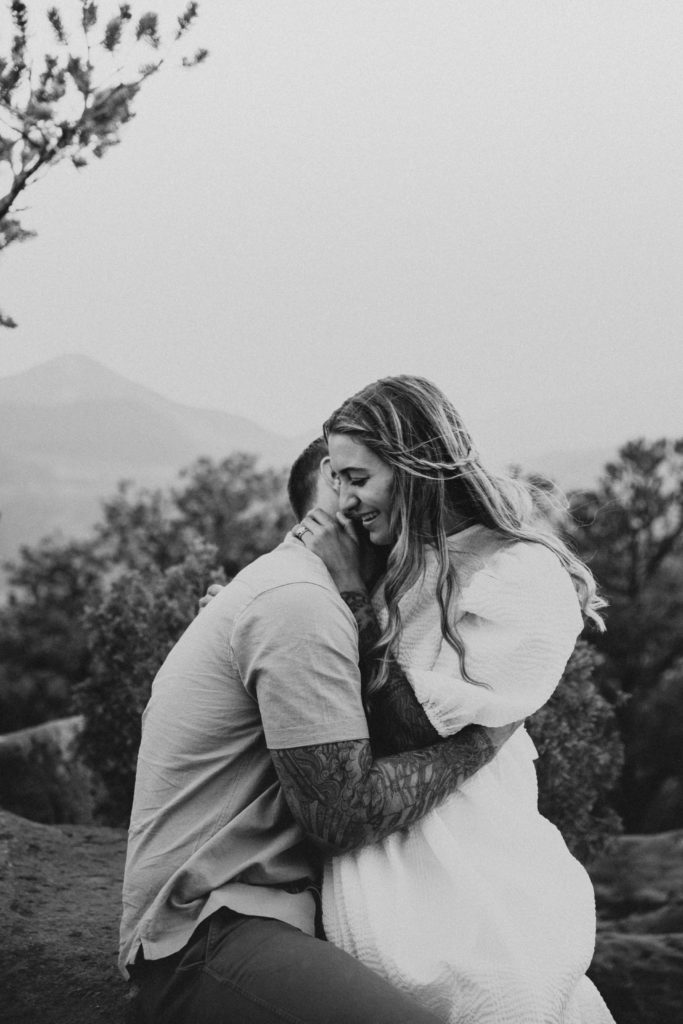 Woman holding on to her partners neck as he kisses her neck during their Colorado engagement session