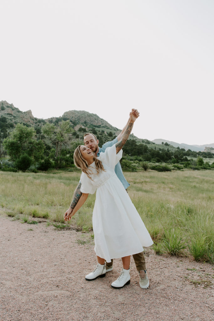 Couple holding hands and having them stretch out acting like they are a plane during their Garden of the Gods engagement photos