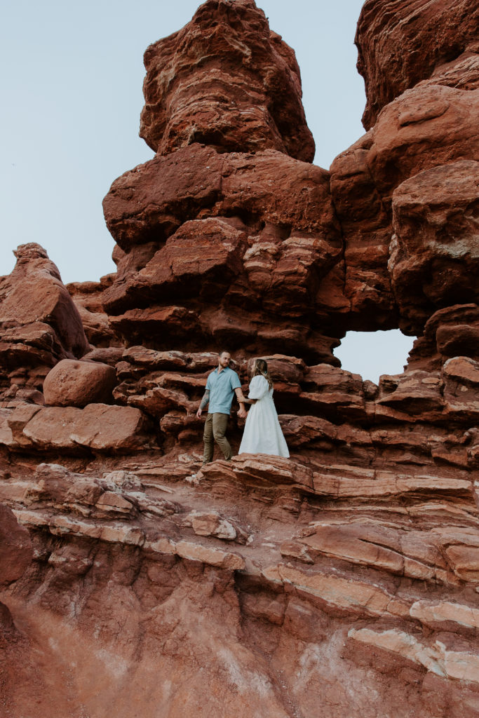 Man leading his partner along the ridges of the red rock formations of Garden of the Gods during their Colorado engagement photos
