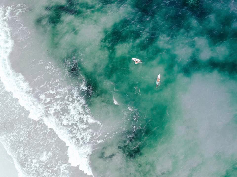 Drone shot of couple surfing in the gulf of mexico during their all day adventurous elopement in Florida 