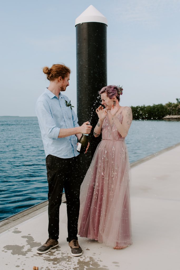 Man spraying his partner with champagne after spending the day exploring key west during their elopement