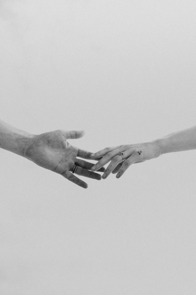 wedding couples hands barely touching in the sky