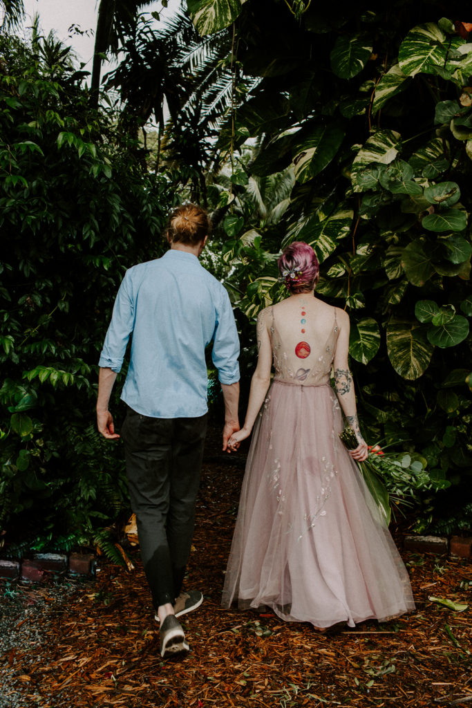 couple holding hands and walking through think trees around the hemingway house