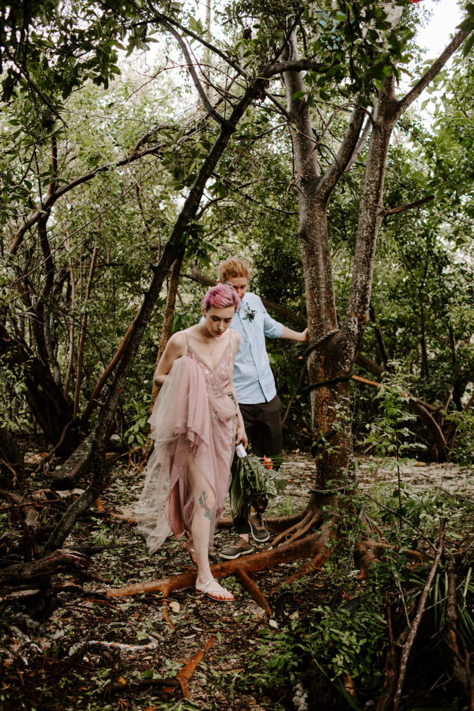 Couple climbing over trees during their elopement to go explore