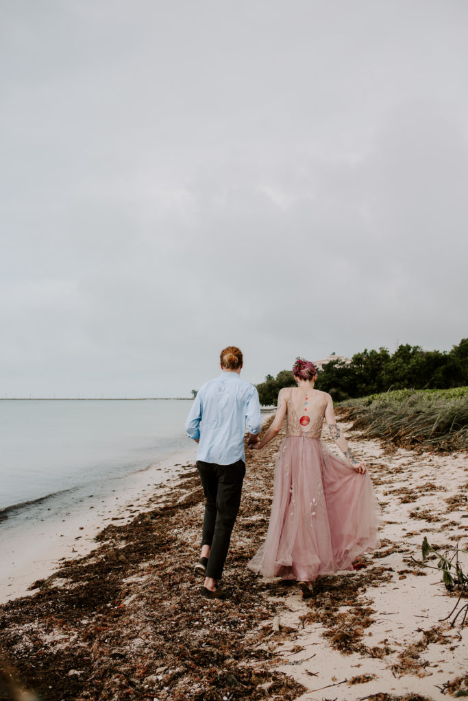 Man and woman holding hands walking along the ocean in Key west during their florida keys elopement