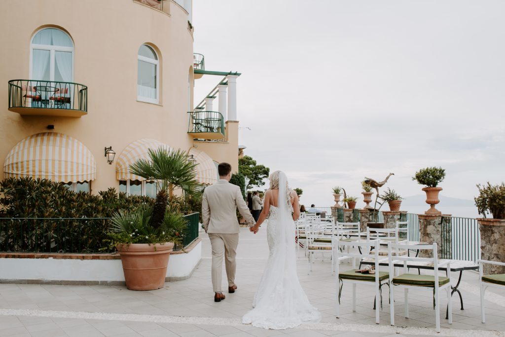 Wedding couple holding hands walking along the edge of their hotel on the Amalfi Coast