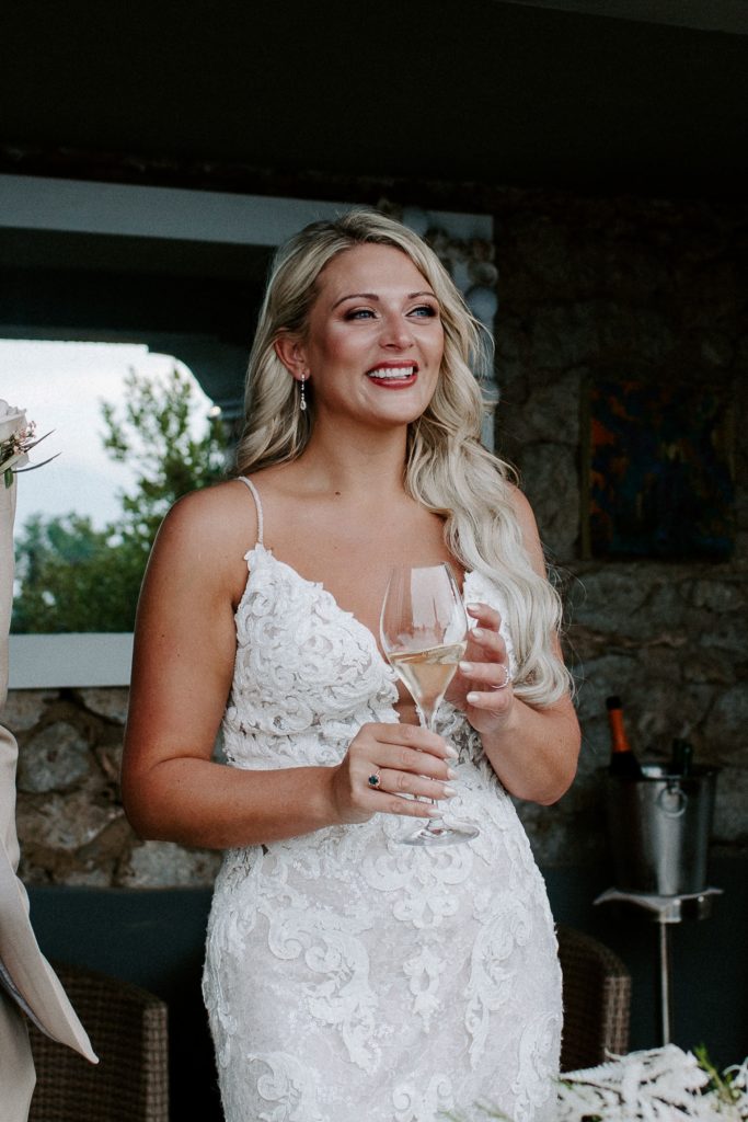 Woman laughing and holding a glass of champagne after her Italian wedding ceremony