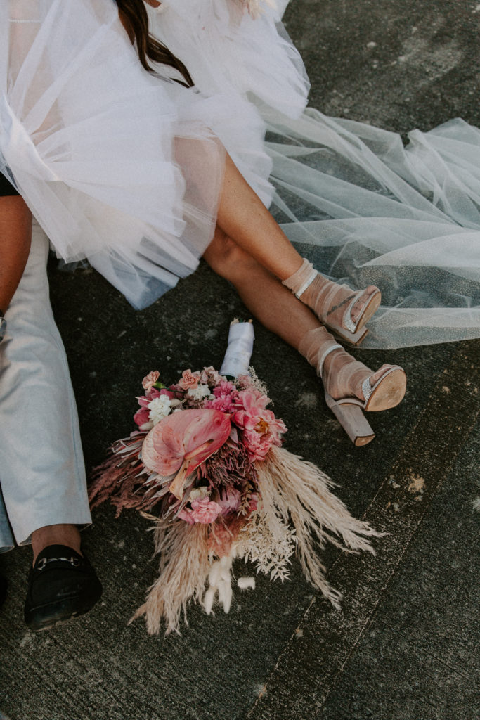 a man and womans feet outlining a pink and red wedding bouquet