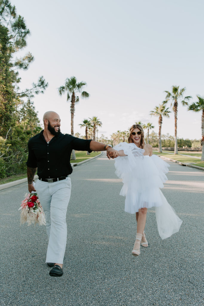 Man looking at his partner as they are holding hands and walking down a road during their Gulf Shores elopement in Alabama  