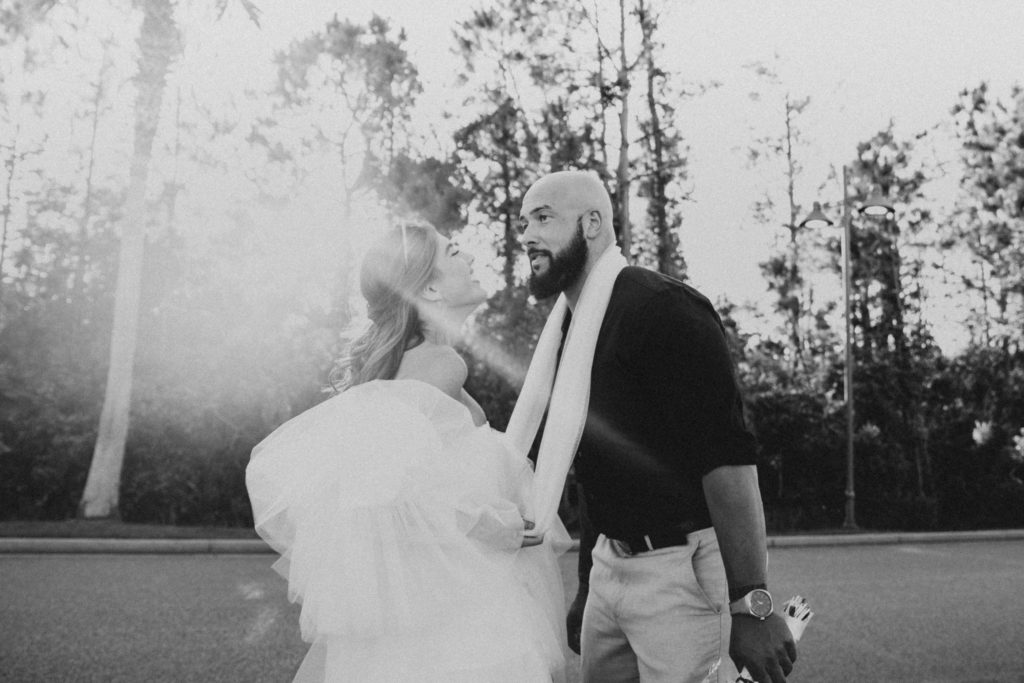 Woman holding her veil around her partner and brings him in closer to her as the sun is setting during their Alabama wedding