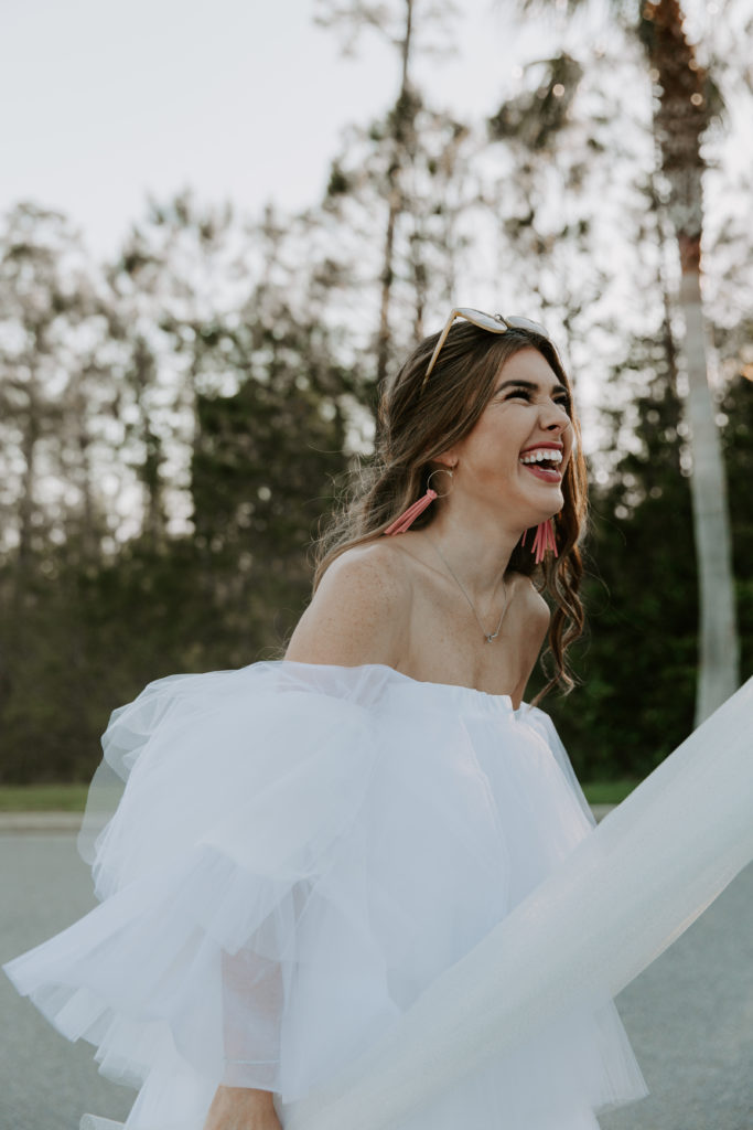 Woman laughing at something her partner said as she is holding her veil around him