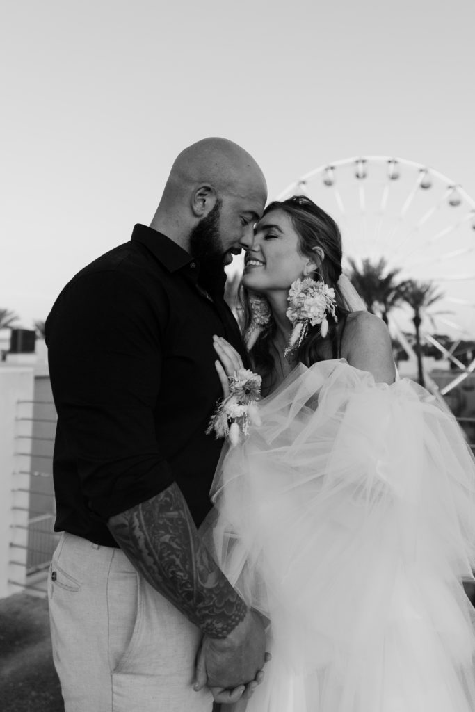 Couple leaning their foreheads together with a ferris wheel behind them during their urban elopement