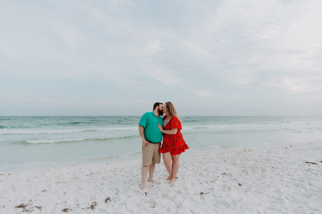 A couple standing on a beach in Destin sharing a kiss as the woman has her hand resting on her partners chest