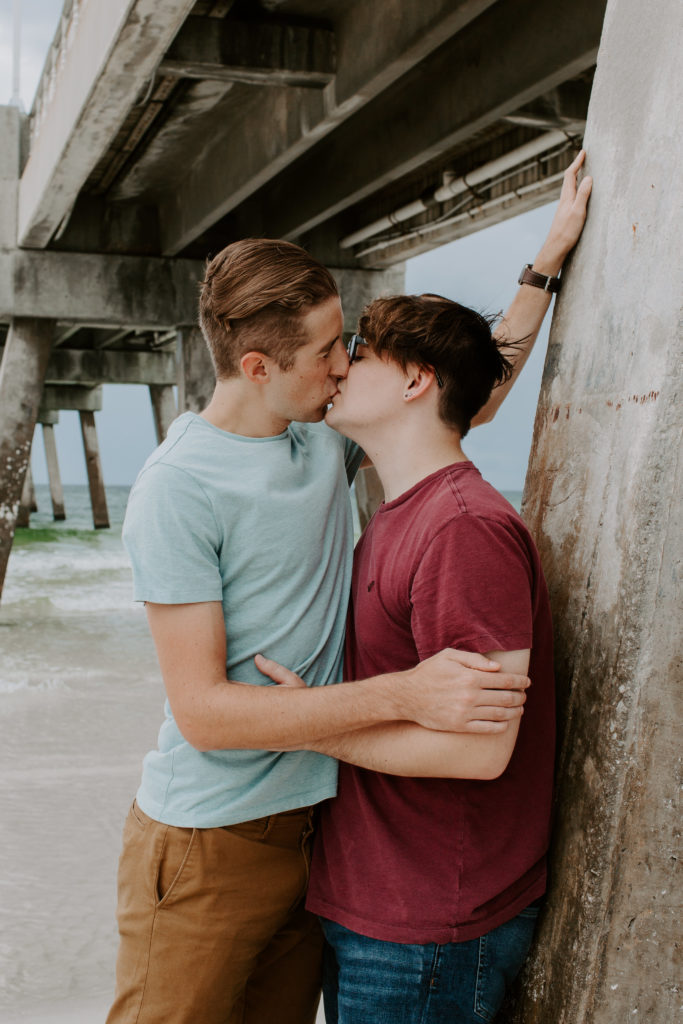 Couple leaning up against the pier while they share a kiss