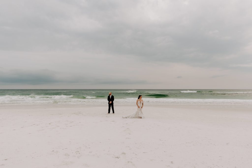 Man and woman standing a few feet apart and looking opposite directions of each other during their sunset beach elopement