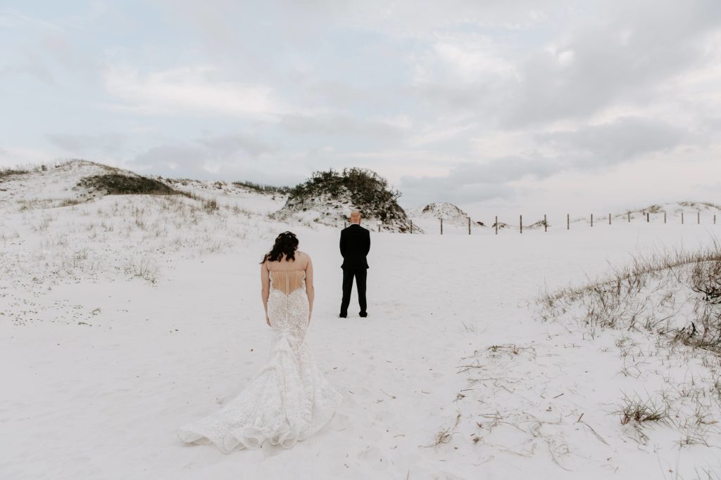 Woman walking up behind her partner as he looks at the sand dunes