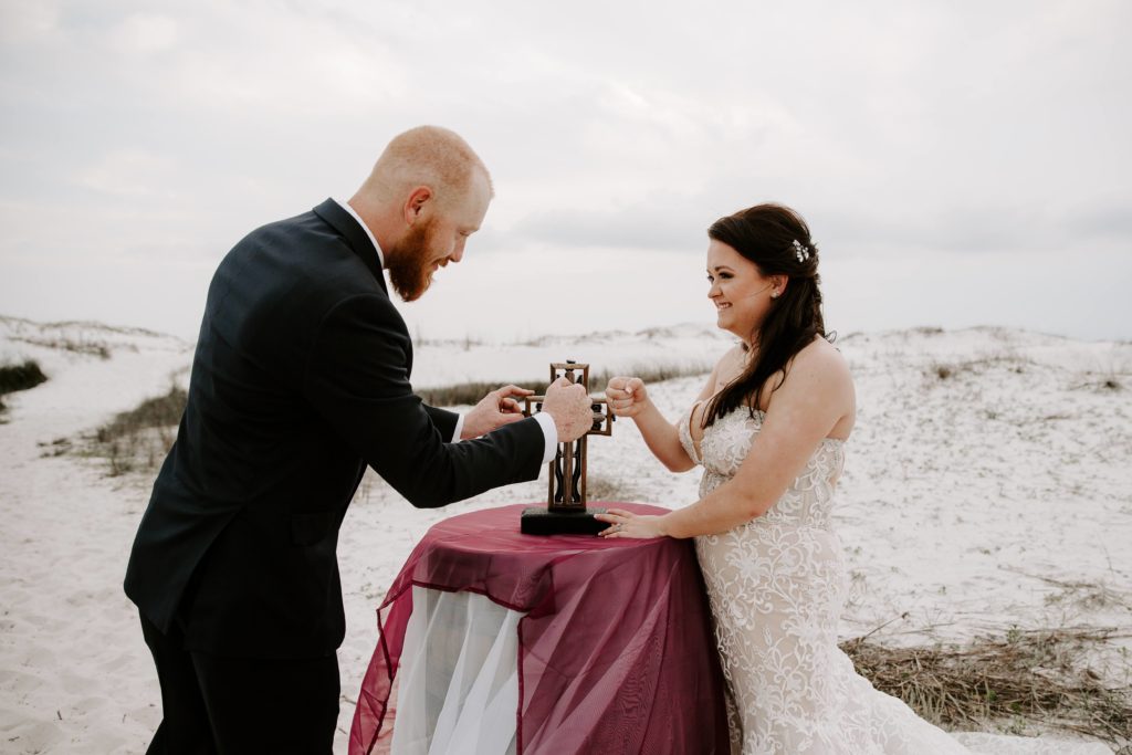 Couple sharing a fist pump after putting together a cross as part of their one year vow renewal on the Emerald Coast in Florida