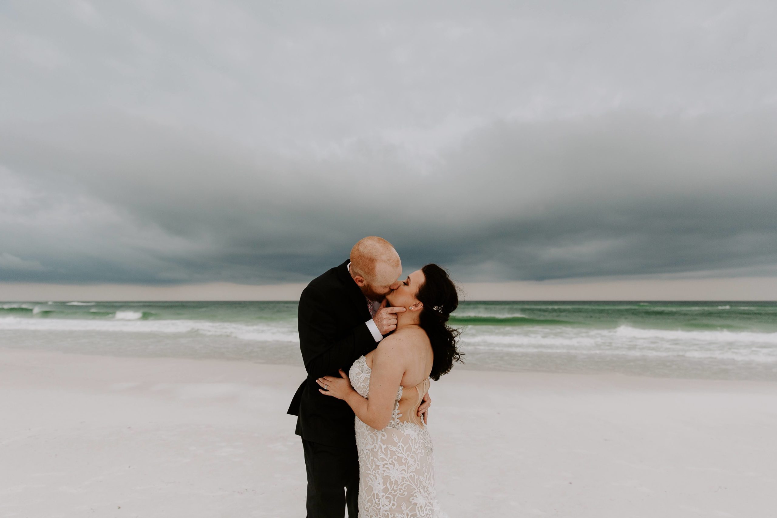 Couple sharing a kiss with a dramatic storm brewing in the background during their one year vow renewal