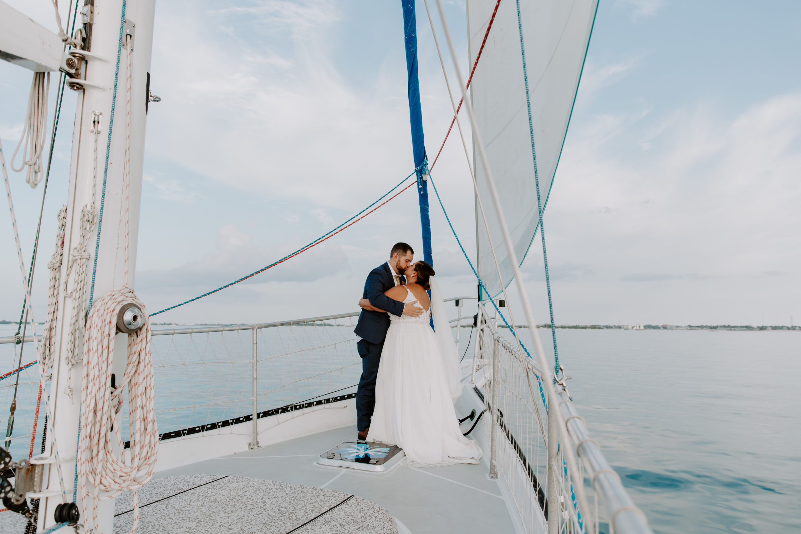 Couple standing at the front of a sail boat sharing a kiss during their sunset cruise during their key west elopement