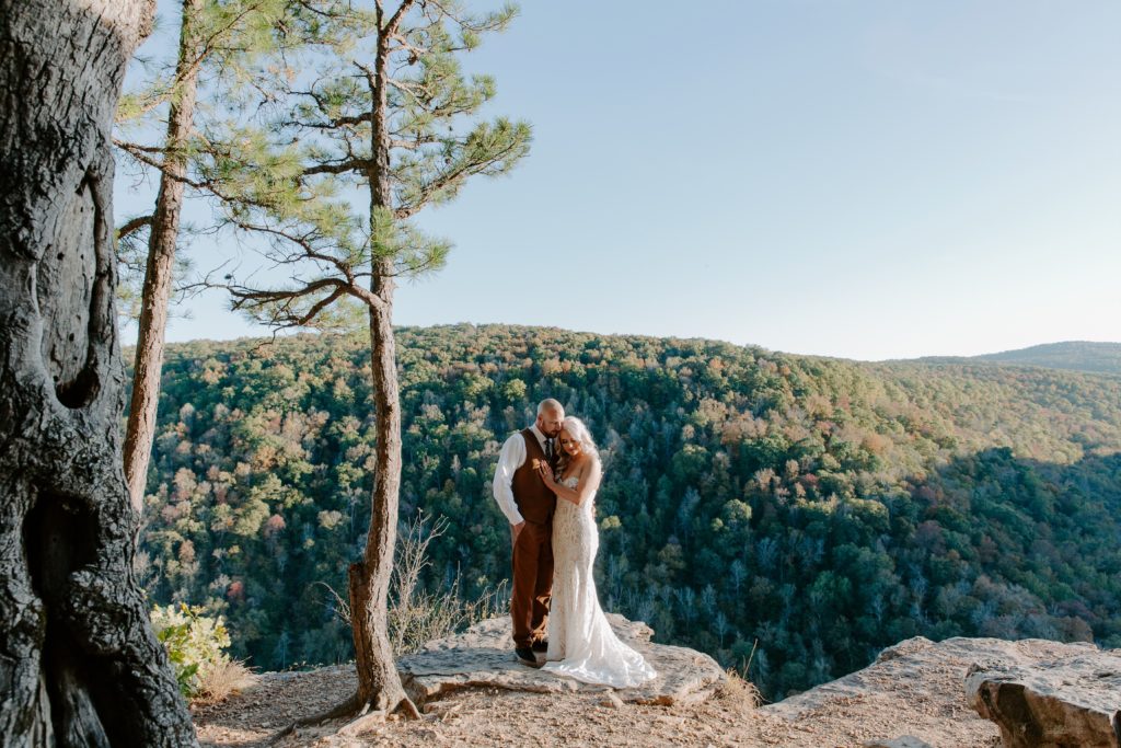 A couple hugging into each other with the colorful trees behind them during their hiking elopement