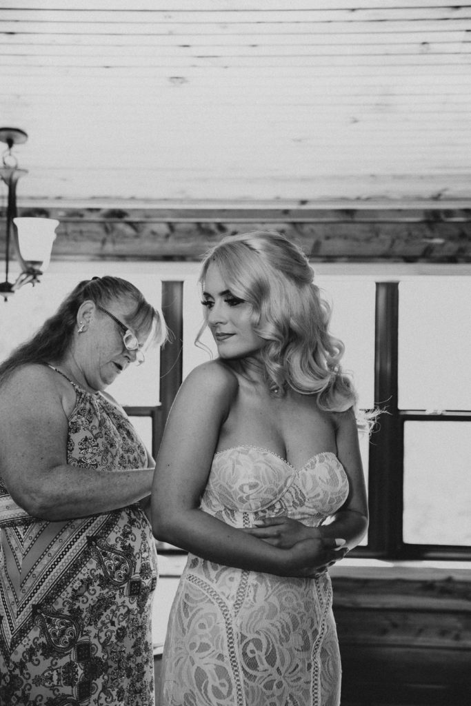 A woman's mother helping her into her wedding dress before their first look at a cabin in the Ozarks