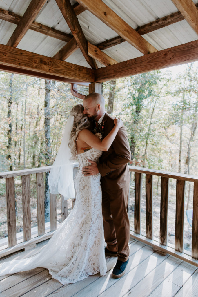 A man hugging his partner at the corner of the cabin they got ready in during their all day Arkansas elopement
