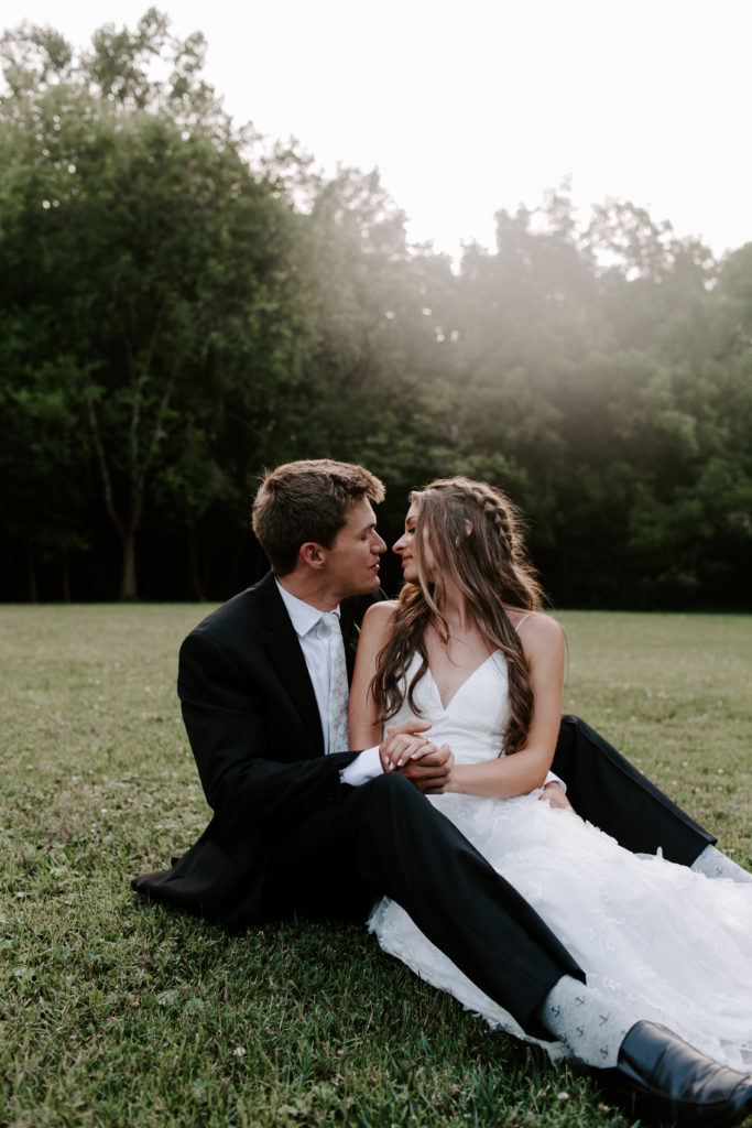 Newly wed couple sitting in a field as they are about to share a kiss during their Tennessee wedding