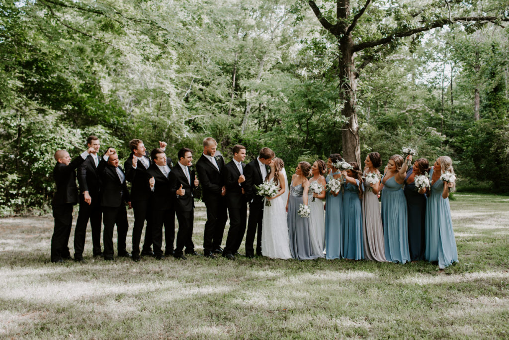 The wedding party cheering on the newly weds as they share a kiss during their summer wedding in Knoxville