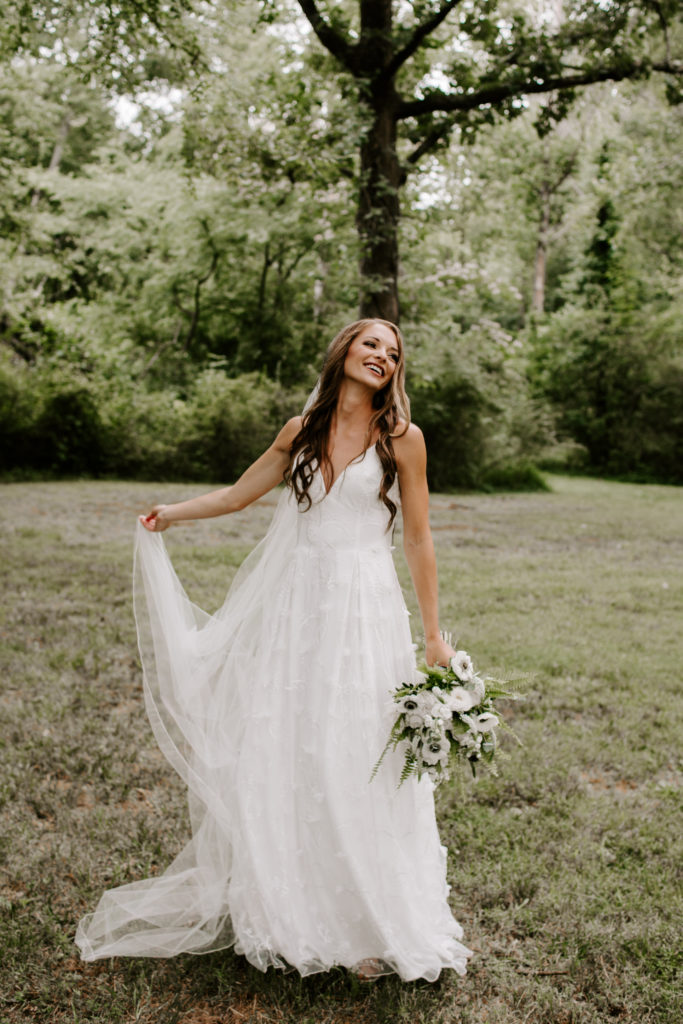 A woman swinging around her wedding dress as she looks off and smiles during her summer wedding in Tennessee