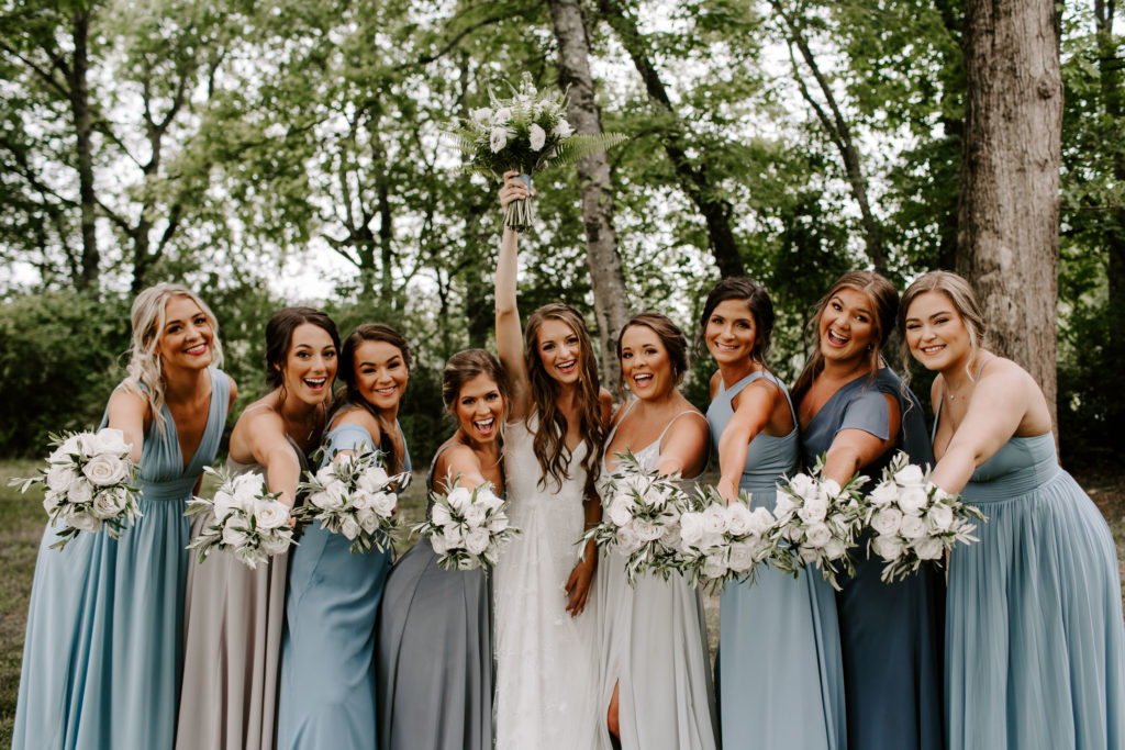 A bride holding her bouquet up in the air as her bridesmaids hold their bouquet out during their Knoxville wedding in Tennessee