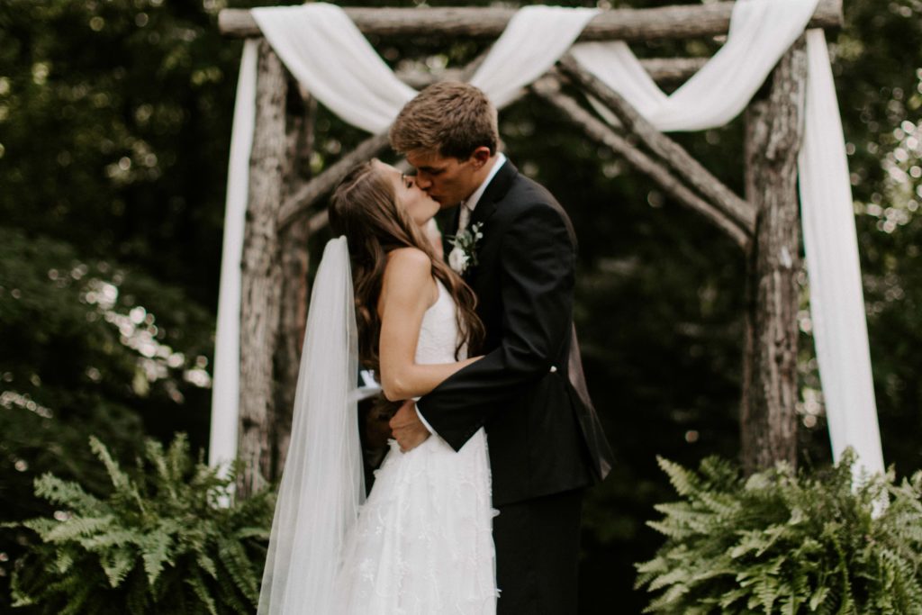 Couple sharing their first kiss under the canopy of the trees during their Tennessee wedding in Knoxville