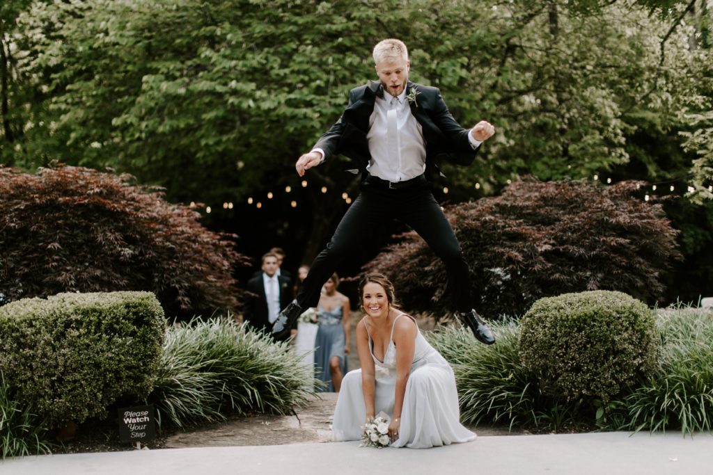 A groomsman jumping over a bridesmaid during their entrance to the wedding reception