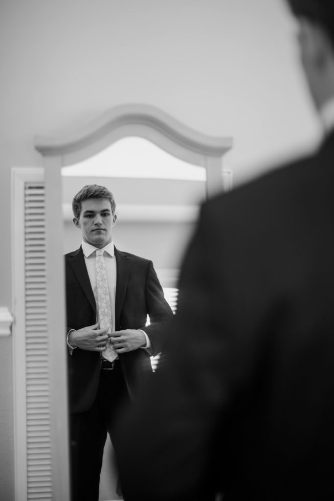 A groom fixing his jacket in a mirror before their Tennessee wedding ceremony