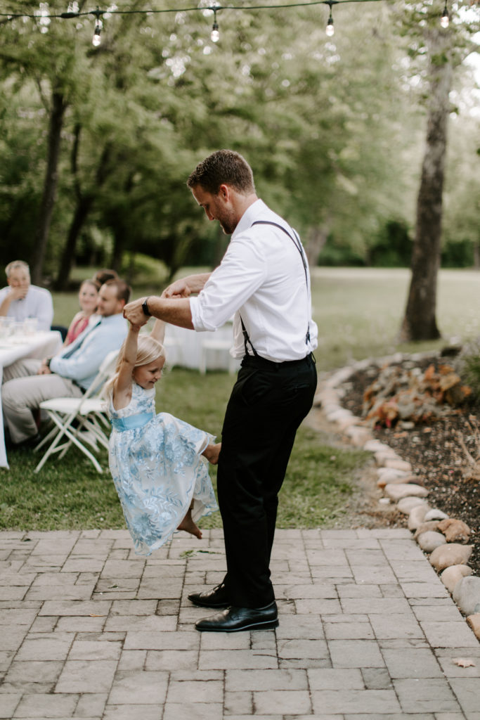 A dad picking his daughter up while she is trying to climb on him during a Knoxville wedding