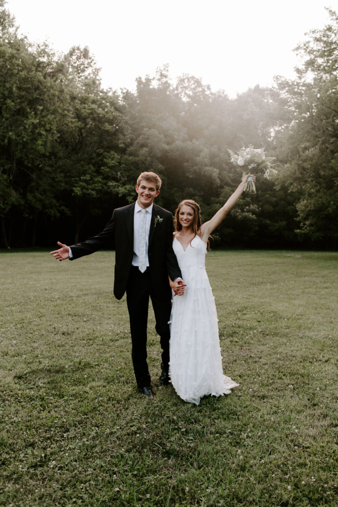 A couple celebrating and throwing their arms in the arm during their knoxville wedding