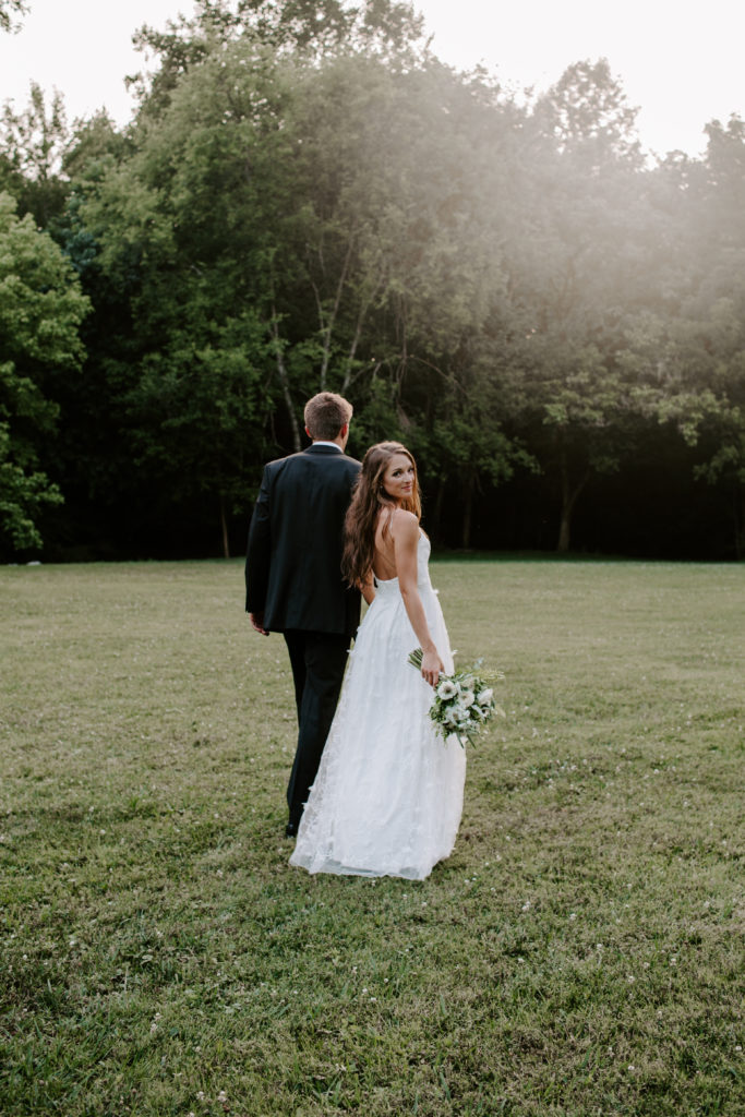 A man leading his partner away as she is looking over her shoulder and holding her wedding bouquet during their east tennessee wedding