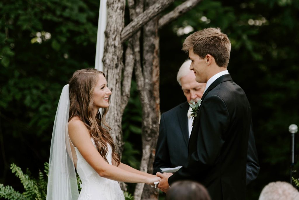 Couple holding hands while the woman is looking lovingly at her partner during their outdoor Tennessee wedding
