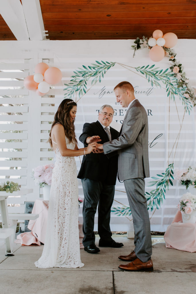 A couple standing with their hands intertwined while the officiant holds his hand over the couples giving them a blessing during their Florida elopement in Destin