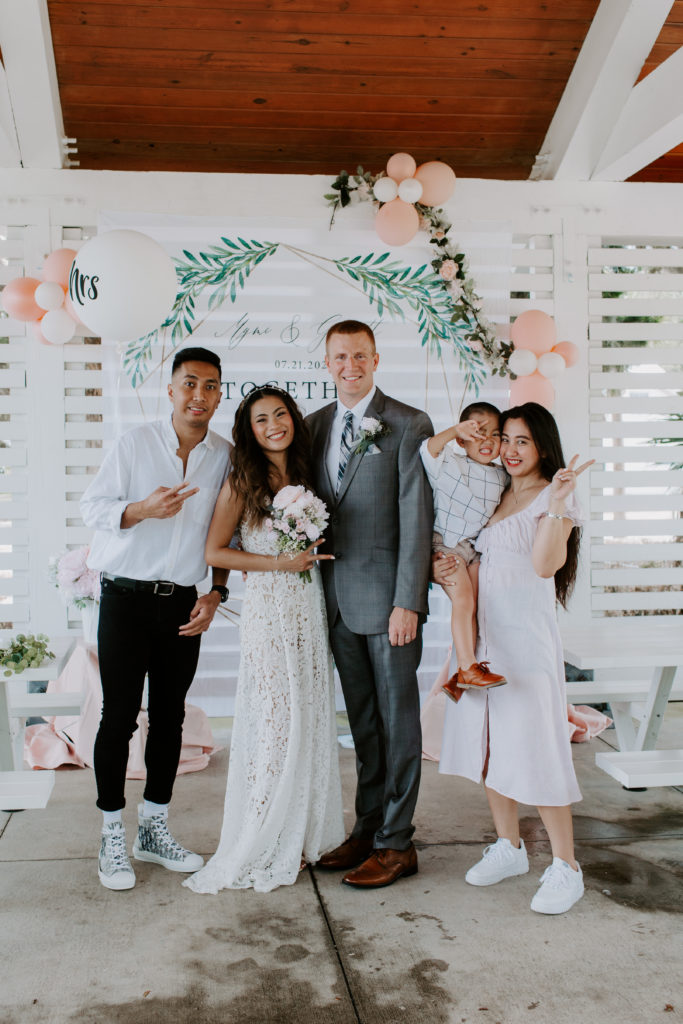 Groom and bride with friends as the boy holds up peace signs during their Florida wedding