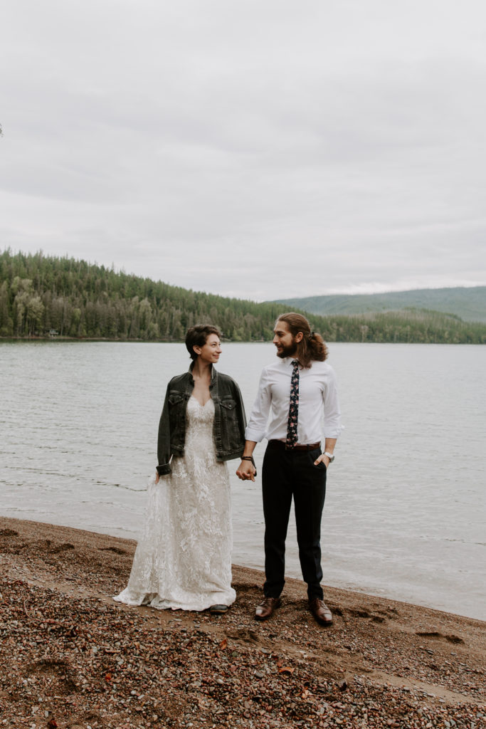 Man and woman holding hands and standing face forward while they are smiling at each other during their glacier national park